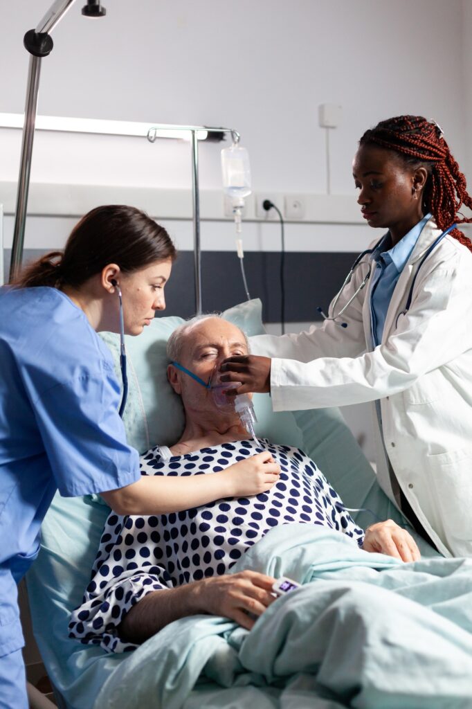 African doctor and medical assistant helping senior man breath